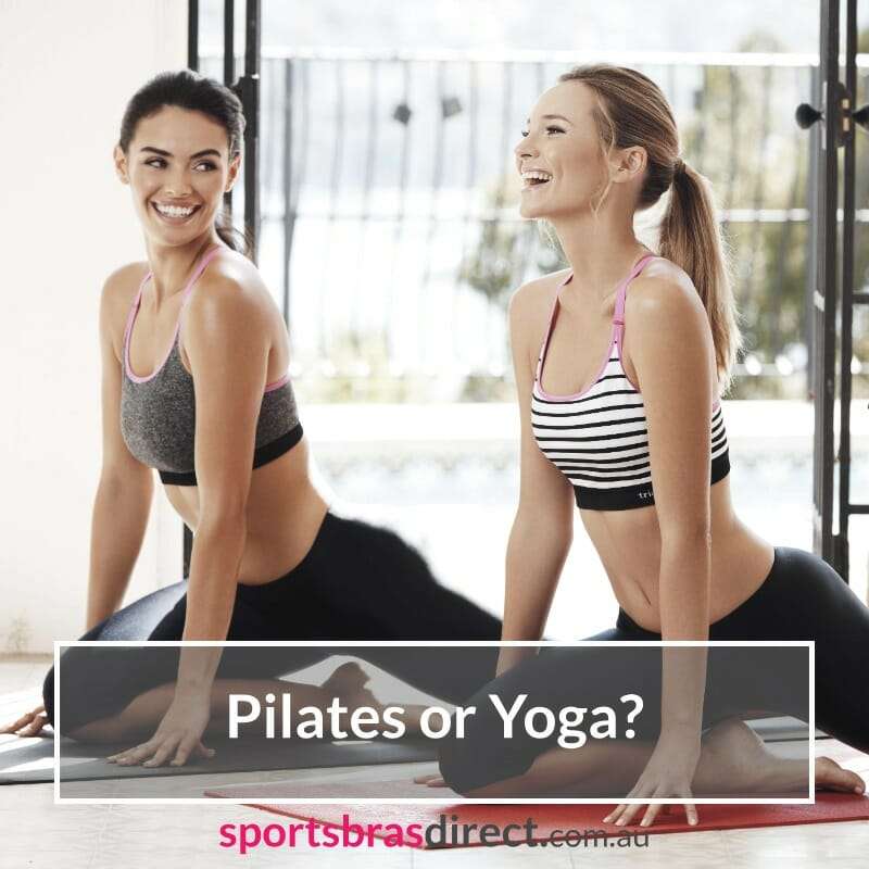 Two women stretching together on yoga mats.