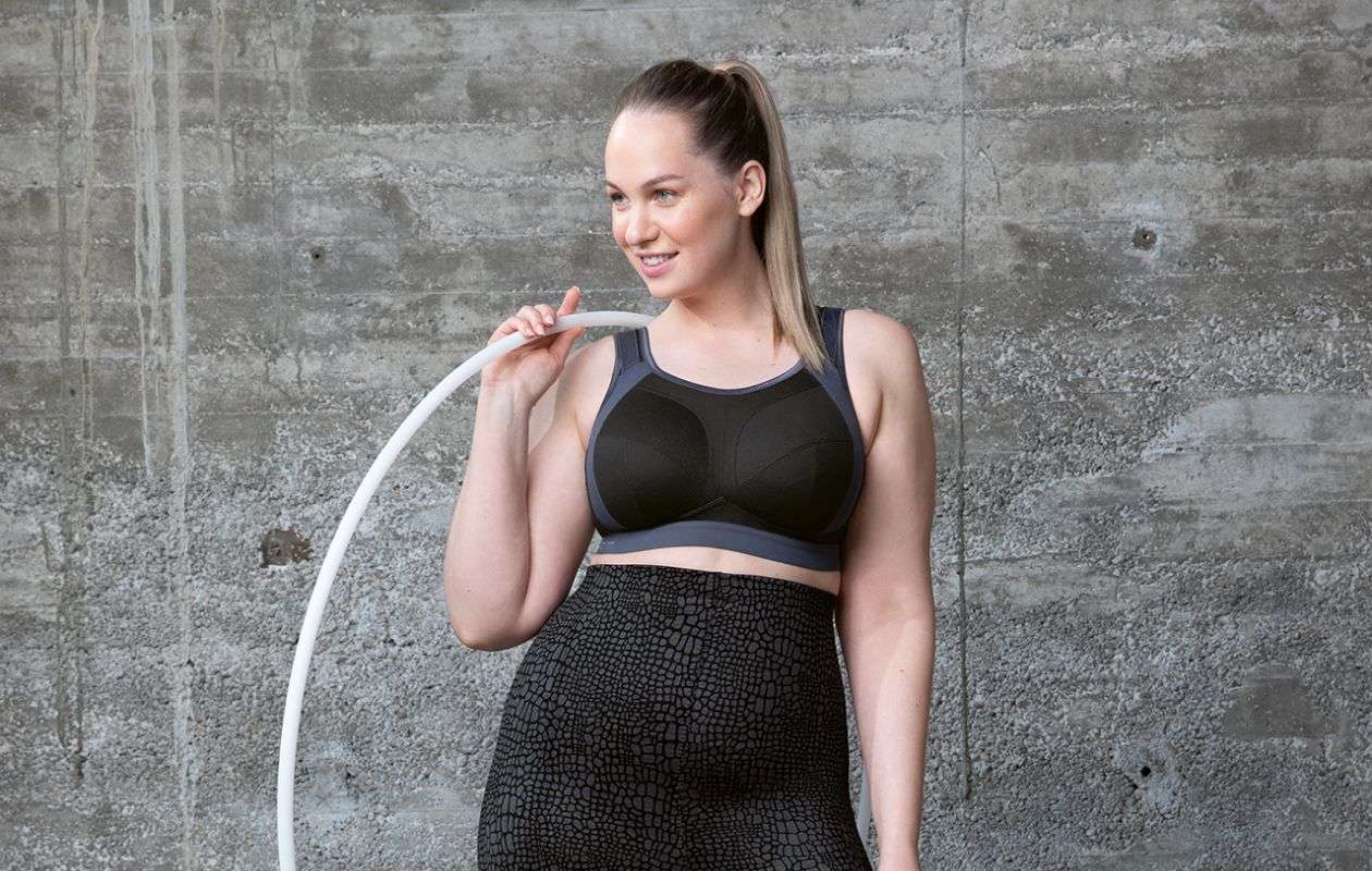Woman wearing a Black sports bra holding a hula hoop.