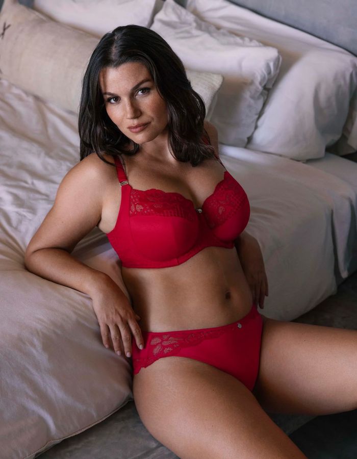 Woman wearing a red lace underwired bra with matching briefs, showing a supportive full cup style.