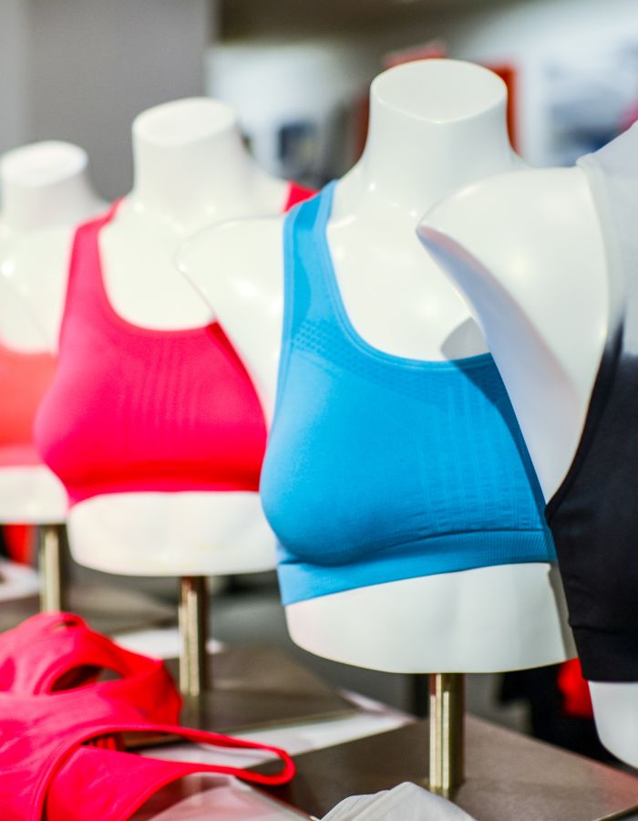 Blue, pink and black sports bras displayed on mannequins, showing different colours and supportive styles.