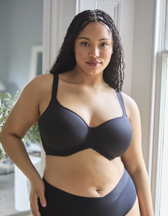 Woman wearing a black moulded underwired bra with full cup coverage and supportive wide straps.