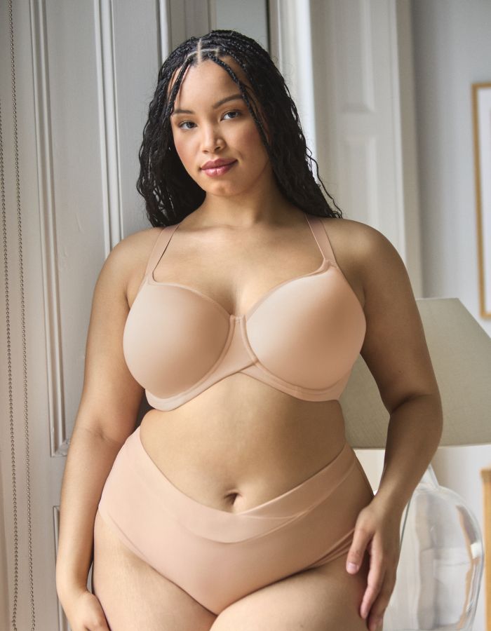 Woman wearing a nude moulded underwired bra with matching briefs, showing a supportive full cup fit.