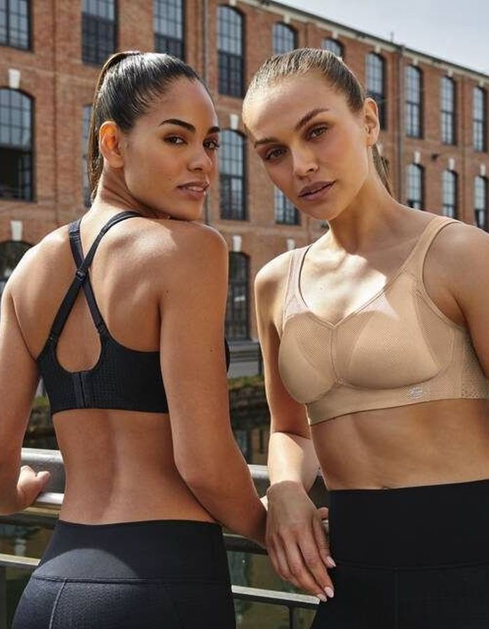 Two women wearing racerback sports bras in black and nude, showing supportive front and back designs for active workouts.