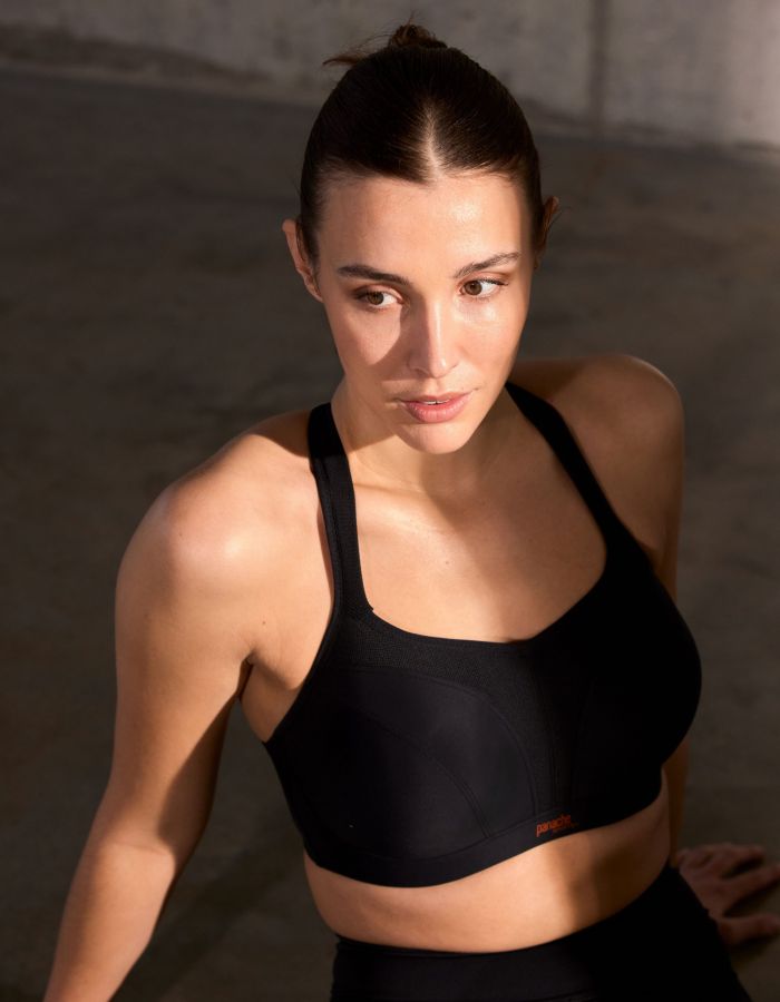 Woman wearing a black supportive sports bra with full coverage cups, designed to provide a secure fit for asymmetrical breasts.